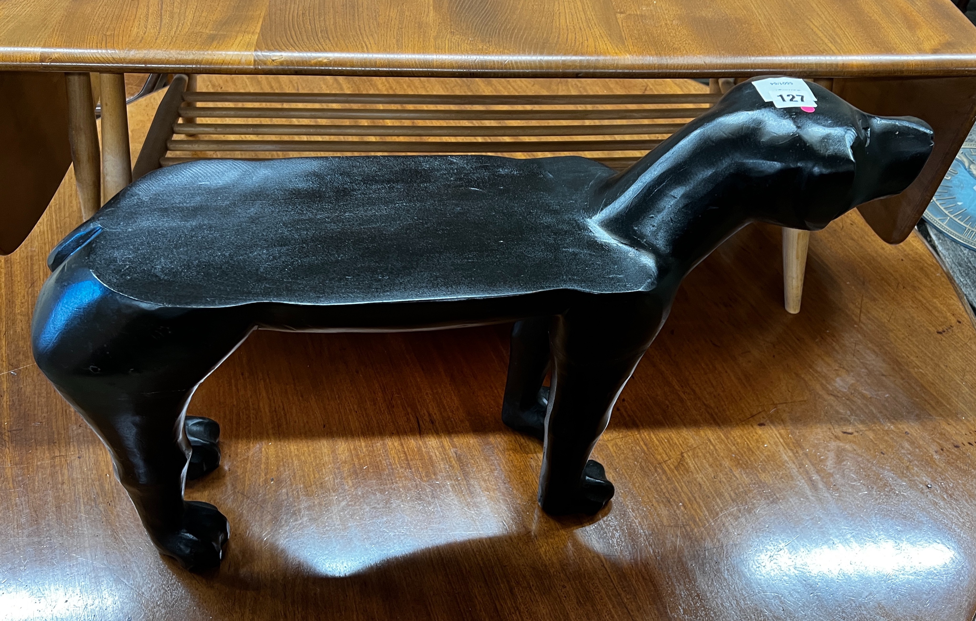 A carved hardwood 'dog' foot stool, with cushion, length 66cm